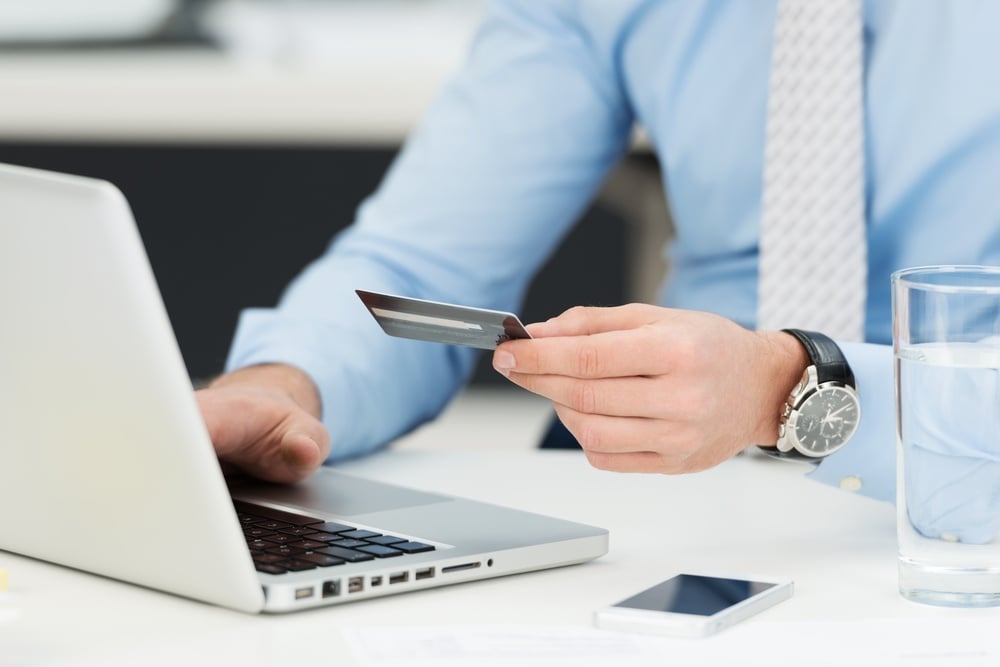 Businessman doing online banking, making a payment or purchasing goods on the internet entering his credit card details on a laptop, close up view of his hands.jpeg