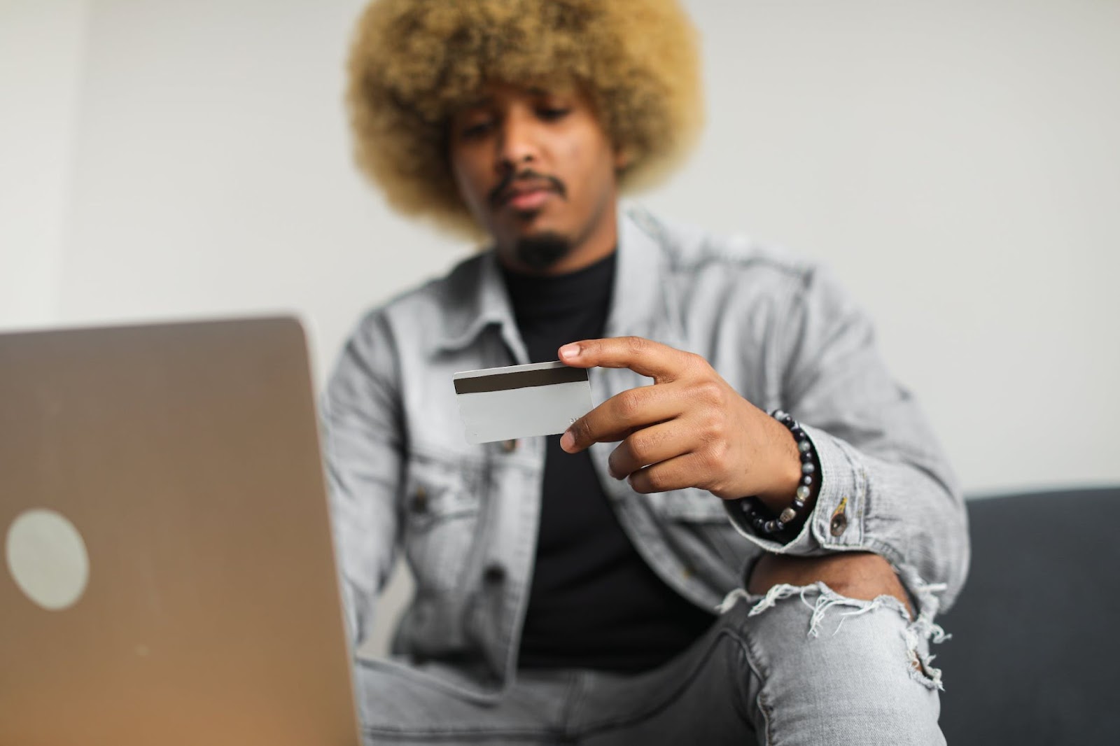 A man with a laptop holding a credit card 
